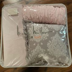 the inside of a suitcase with pink and white items in it on top of a wooden floor