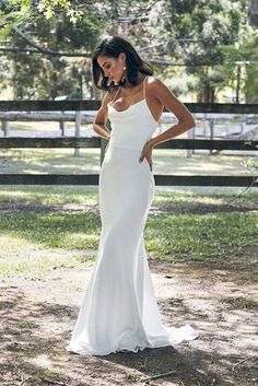 a woman in a white wedding dress standing on the ground with her hands on her hips