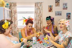 four women are sitting at a table together and having fun playing with their jewelry pieces