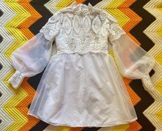 a white dress is laying on top of a chevron rug with an orange and yellow stripe