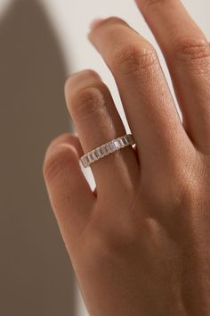 a woman's hand with a wedding band on her finger and the ring is in white gold