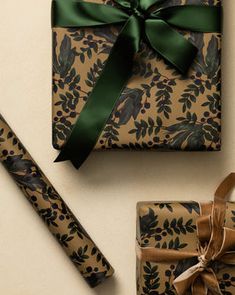 a present wrapped in brown paper with a green ribbon and matching gift wrapper next to it