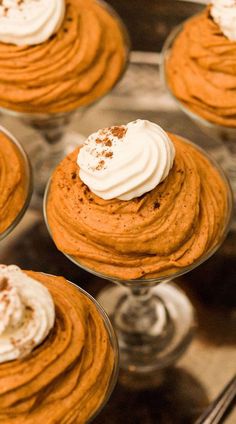 several small desserts with whipped cream and pumpkin cheesecake frosting in glass dishes