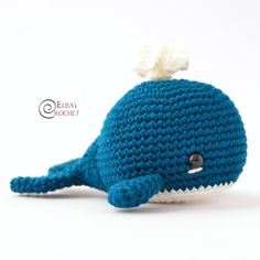 a crocheted blue whale stuffed animal with a white tail and nose is shown