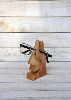 a wooden head with glasses on it sitting on top of a white wood floor next to a pair of glasses