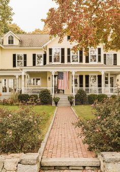 a large yellow house with an american flag on the front porch and steps leading up to it