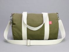 a green and white duffel bag sitting on top of a gray floor next to a wall