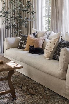 a living room with a couch, coffee table and large window covered in drapes