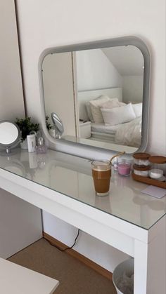 a white dressing table with a mirror on it and some cups in front of it