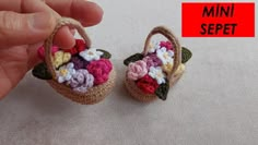 small crocheted basket with flowers on it being held by someone's hand