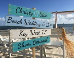 a beach wedding sign on the sand with chairs in the foreground and blue sky in the background