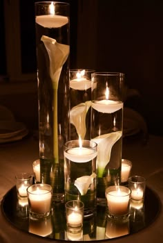 flowers and candles are arranged in glass vases