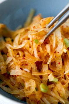 a close up of a bowl of food with chopsticks in it and noodles