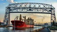 a large red boat in the water under a bridge