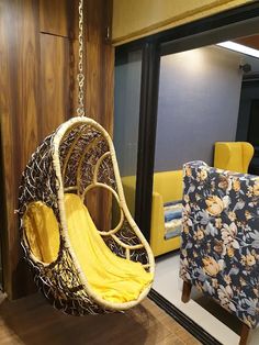 a yellow swing chair hanging from the ceiling in a living room with wood paneling