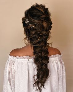 a woman with long hair in a half - up braid wearing a white blouse and pearls