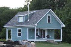 a blue house sitting in the middle of a lush green field