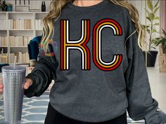 a woman wearing a sweatshirt with the letter rc on it and holding a drink in her hand