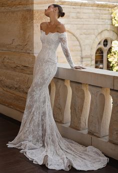 a woman in a white wedding dress leaning on a balcony railing with her hand on her hip