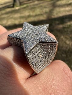 a person is holding up a ring with a star design on it's middle finger