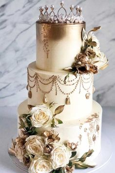 a three tiered wedding cake with white flowers and gold decorations on the top layer