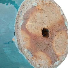 an old, rusted metal object is shown in the middle of blue water and dirt