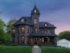 a large gray house sitting on top of a lush green field