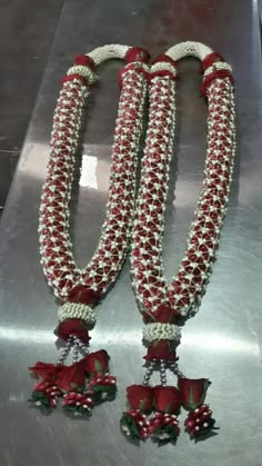 two red and white necklaces with bells attached to them on a metal surface,