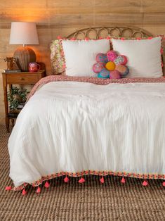 a white bed with pink pom poms on it