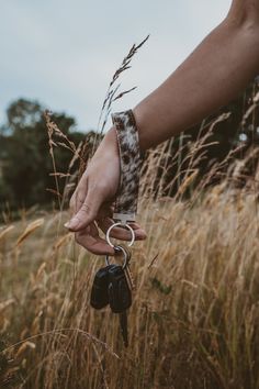 a person holding a car key in their hand while standing in the middle of tall grass