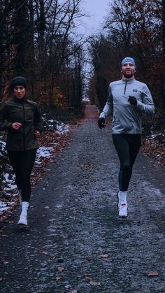 two people running down a path in the woods on a cold day with no shoes