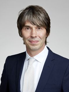 a man in a suit and tie smiling for the camera