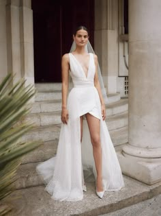 a woman in a white wedding dress standing on steps with her legs crossed and wearing a veil