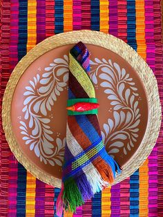 a plate with a colorful decoration on it and a straw hat hanging from the rim