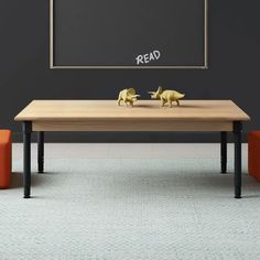 a table with two elephants on it in front of a blackboard and orange chairs