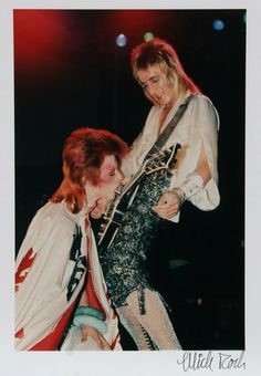 an old black and white photo of two people on stage with one person touching the other's neck