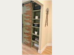 an open bookcase in the corner of a room next to a wall mounted clock