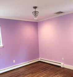 an empty room with purple walls and wood floors