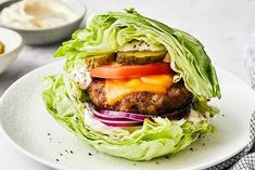 a hamburger with lettuce, tomato and cheese on it sitting on a plate