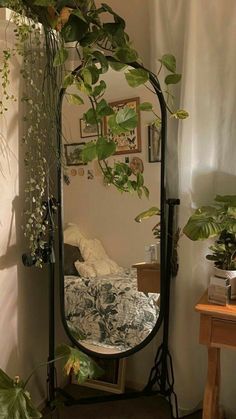 there is a mirror in the corner with some plants on it and a table next to it