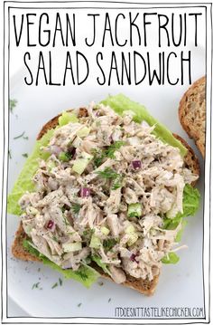 a sandwich with chicken salad and lettuce is on a white plate next to bread