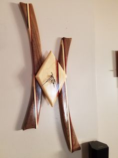 a wooden clock mounted to the side of a white wall next to a black speaker