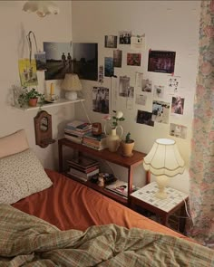 a bed with an orange comforter and some pictures hanging on the wall above it