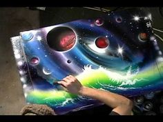 a woman holding up a large painting with space and planets in the background on it