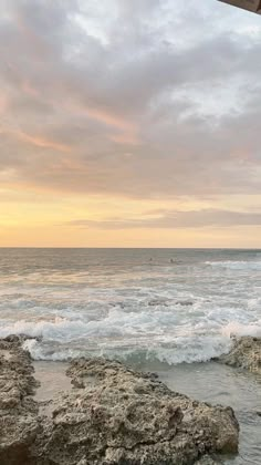 an umbrella sitting on top of a rock next to the ocean under a cloudy sky