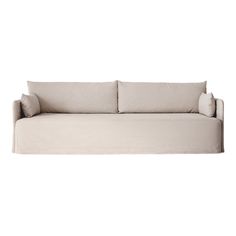 a white couch sitting on top of a white floor next to a pillow and pillows