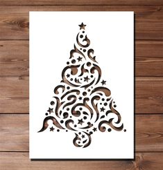 a christmas tree with swirls and stars on white paper in front of wooden background