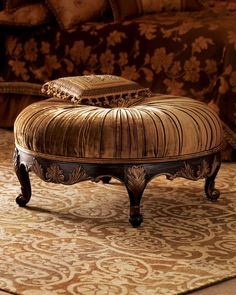 an ornate ottoman sits on top of a rug in front of a couch with pillows