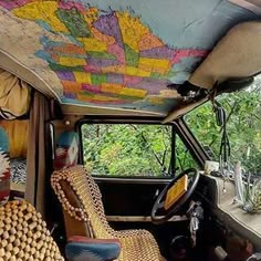 the interior of an old bus is decorated with colorful maps and wicker furniture,