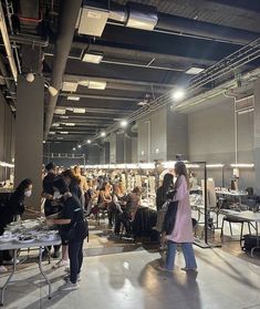 people are sitting at tables in an open space with lots of lights hanging from the ceiling